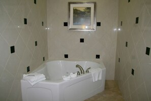 A bathroom with a large bathtub, a framed picture on the wall, and a tiled floor.