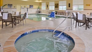 Un espace piscine d’hôtel comprenant un jacuzzi, des chaises longues et des tables.