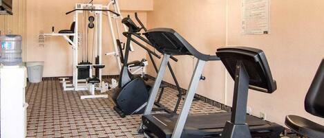 Un gimnasio con cintas de correr, elípticas y equipo de levantamiento de pesas.