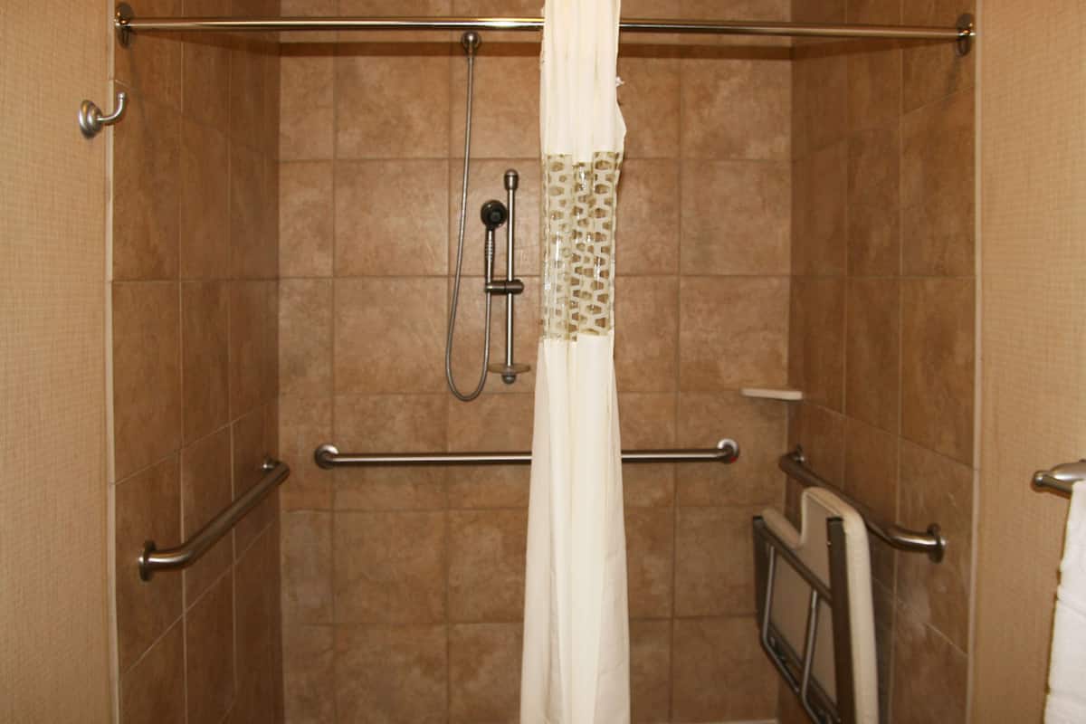A shower area with a grab bar, a showerhead, and a towel rack.