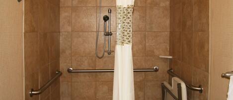 A shower area with a grab bar, a showerhead, and a towel rack.