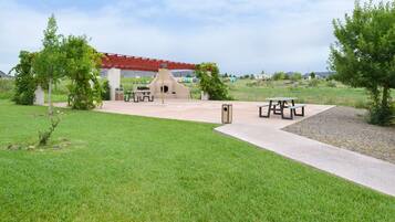Relax in a serene outdoor setting with a lawn, picnic table, and barbecue grill under a pavilion.