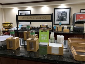 A breakfast bar with various food and drink options, including juice dispensers and containers.