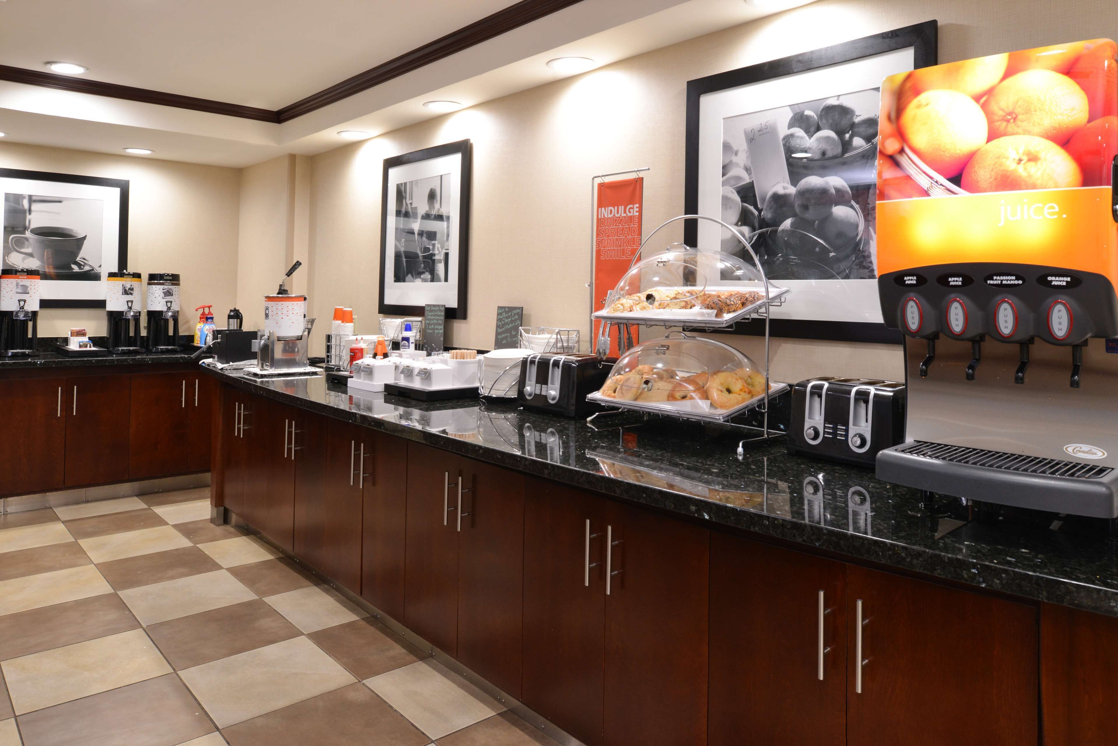 A hotel kitchen with a buffet setup, including a juice dispenser, a coffee station, and a variety of food items.