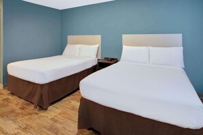 Two single beds with brown headboards and white bedding in a room with blue walls and wooden flooring.