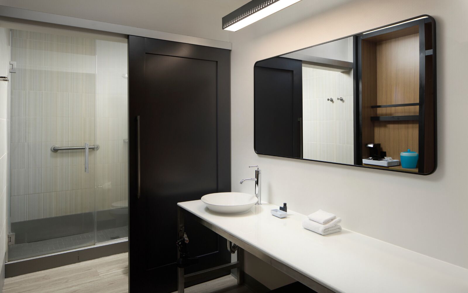 A modern bathroom with a glass shower, a white sink, and a large mirror.