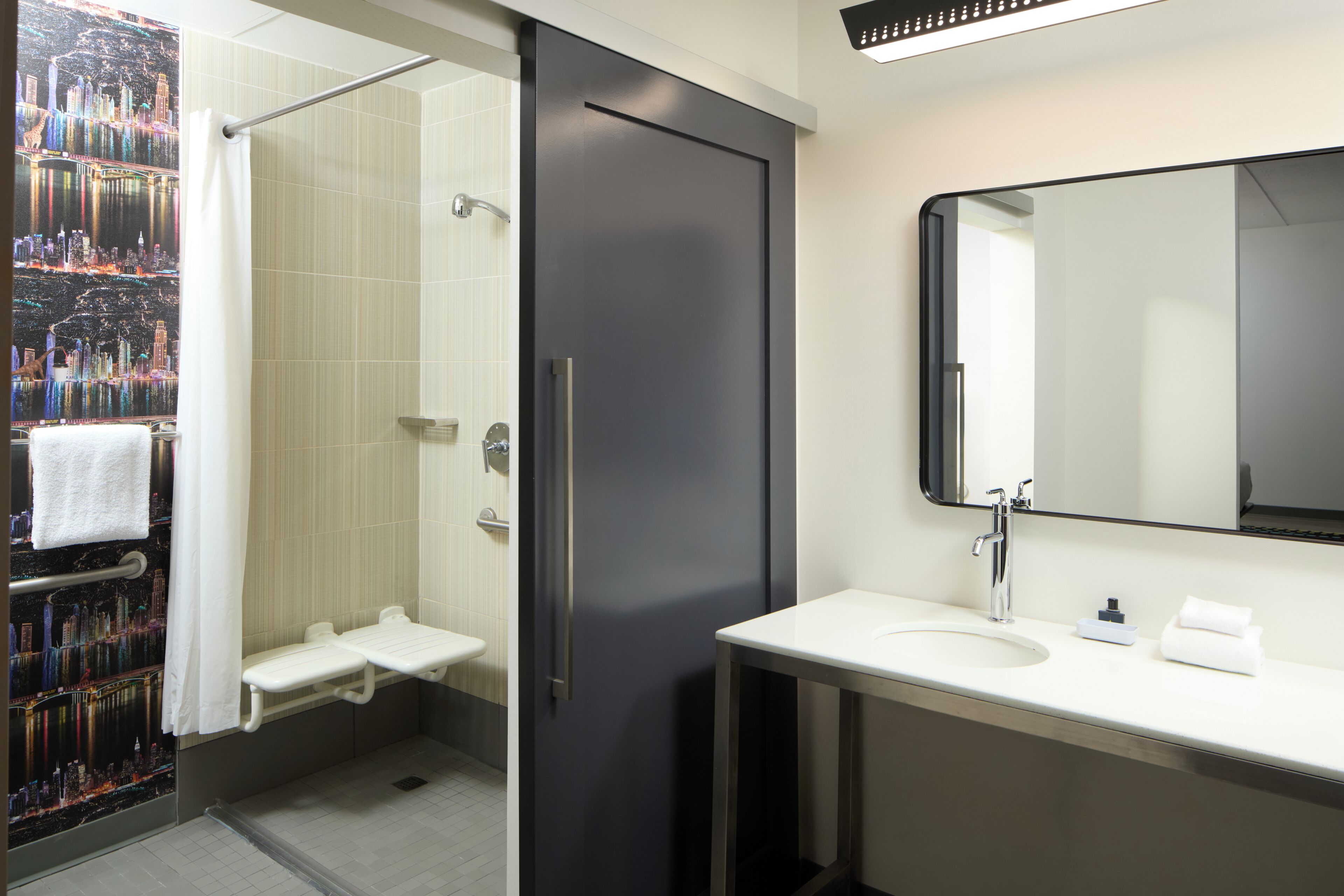 Un baño moderno con ducha, lavabo y un espejo grande.