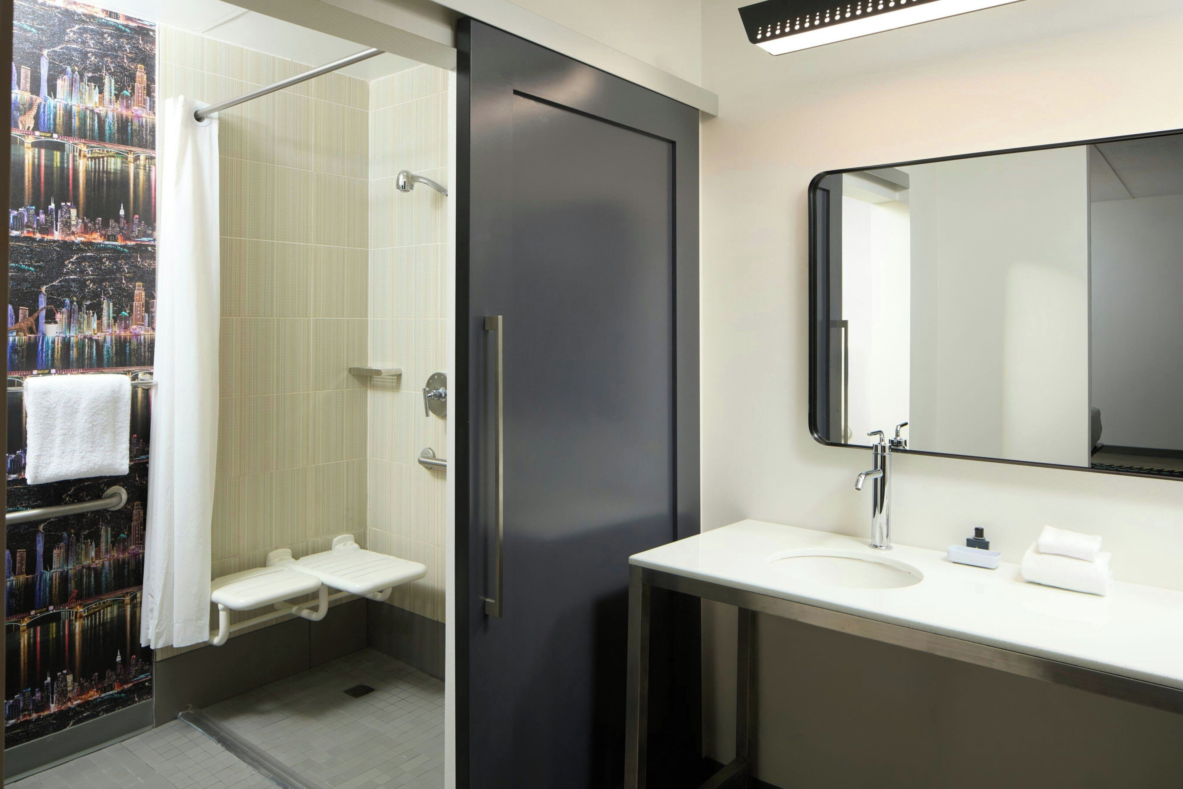 A modern bathroom with a shower, a sink, and a mirror.