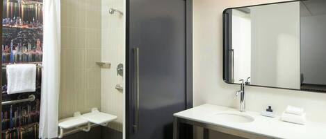 Un baño moderno con ducha, lavamanos y espejo.