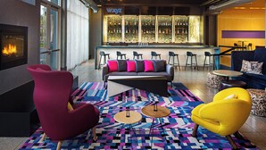 A modern bar area with a bar counter, seating, and a fireplace. - Aloft by Marriott Tempe (Tempe)