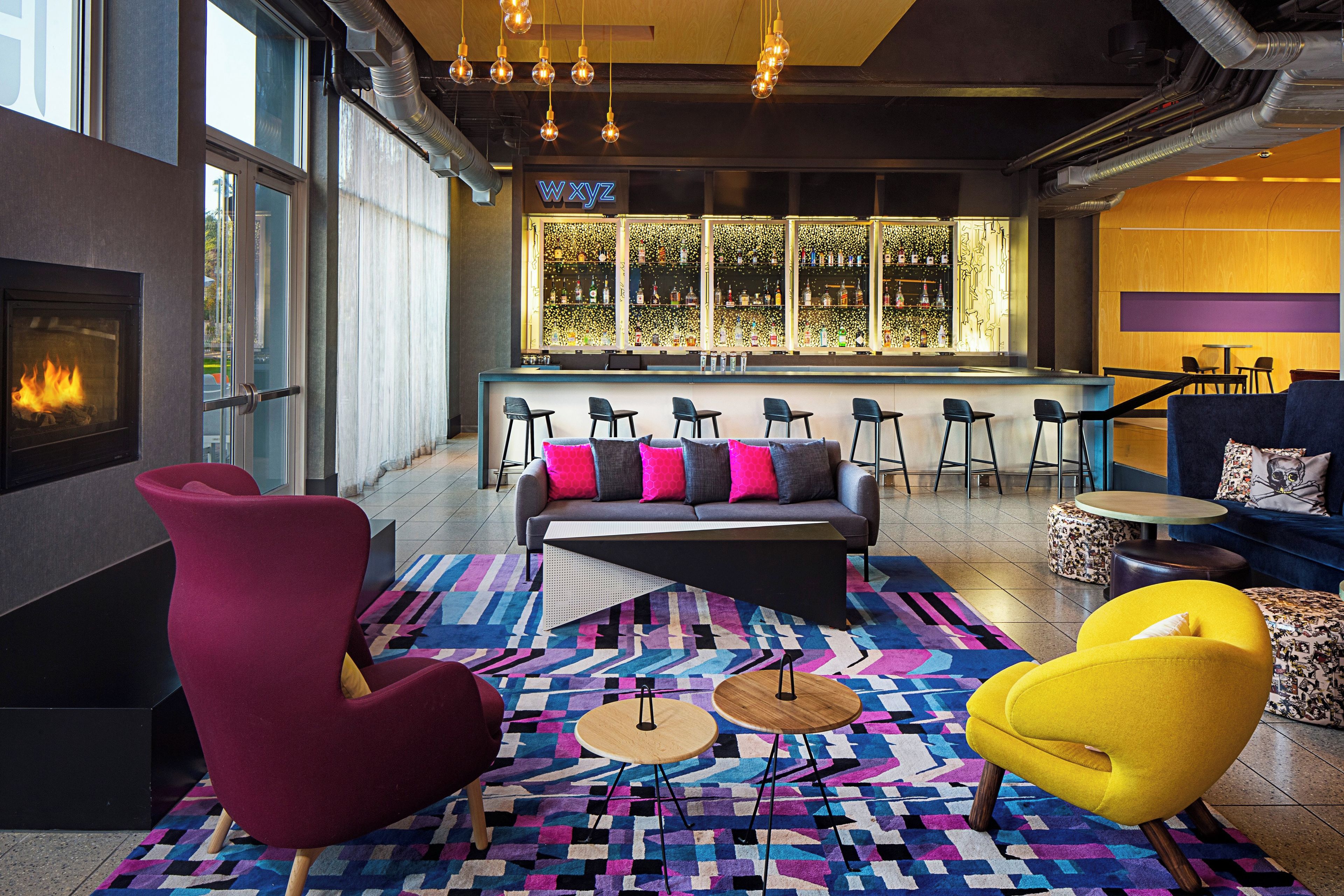 A modern lounge area with a fireplace, seating, and a bar with a decorative backdrop.