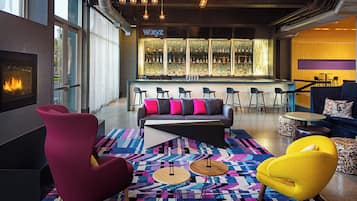 A modern lounge area with a fireplace, seating, and a bar with a decorative backdrop.