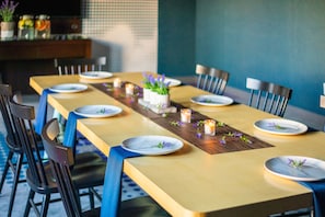 A dining table set with plates, candles, and small potted plants. - Aloft by Marriott Tempe (Tempe)