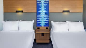 A hotel room with two beds, a central wall art piece, and bedside lamps.