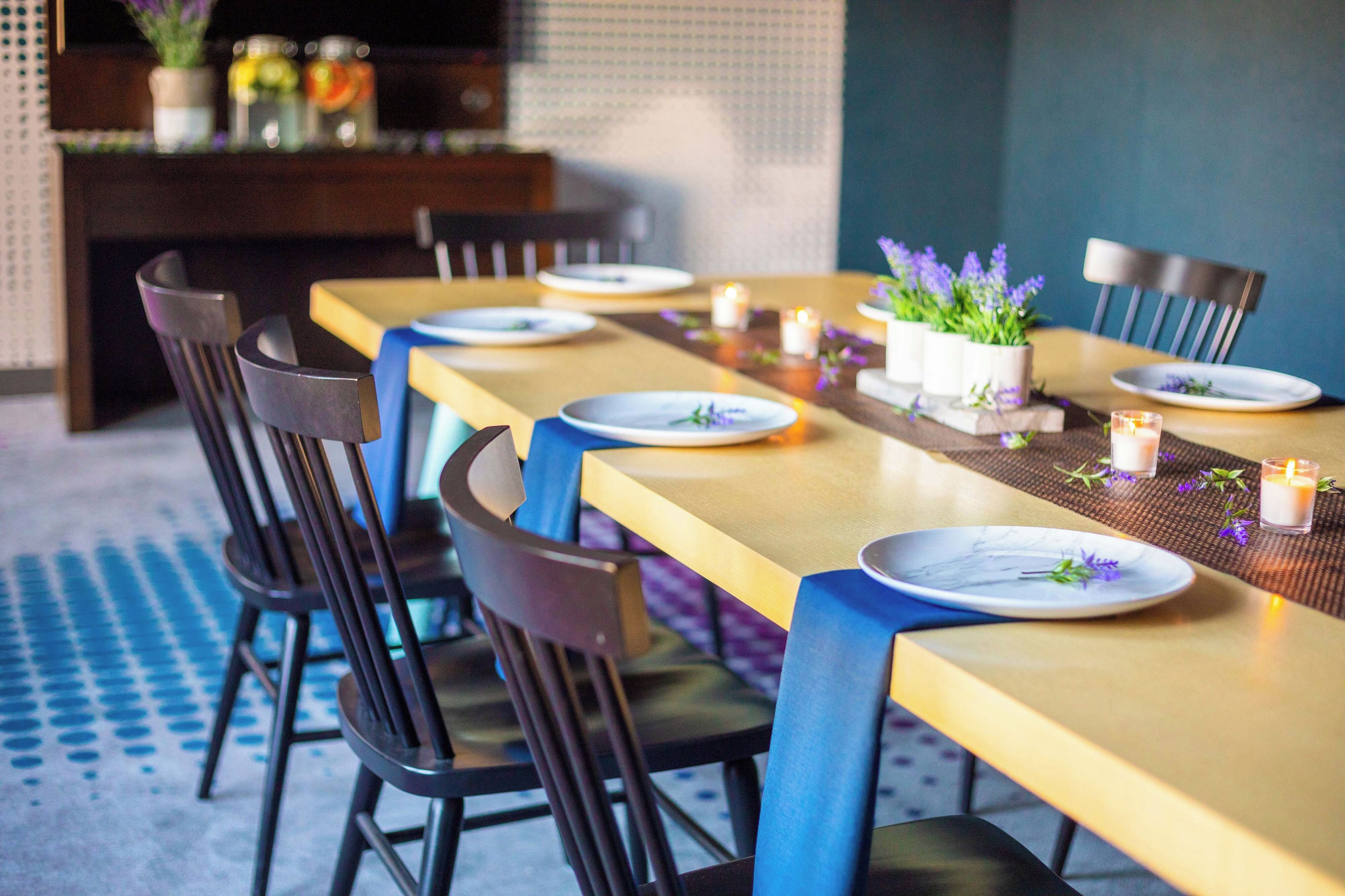 Un comedor con una larga mesa dispuesta para varios invitados, sillas y velas.