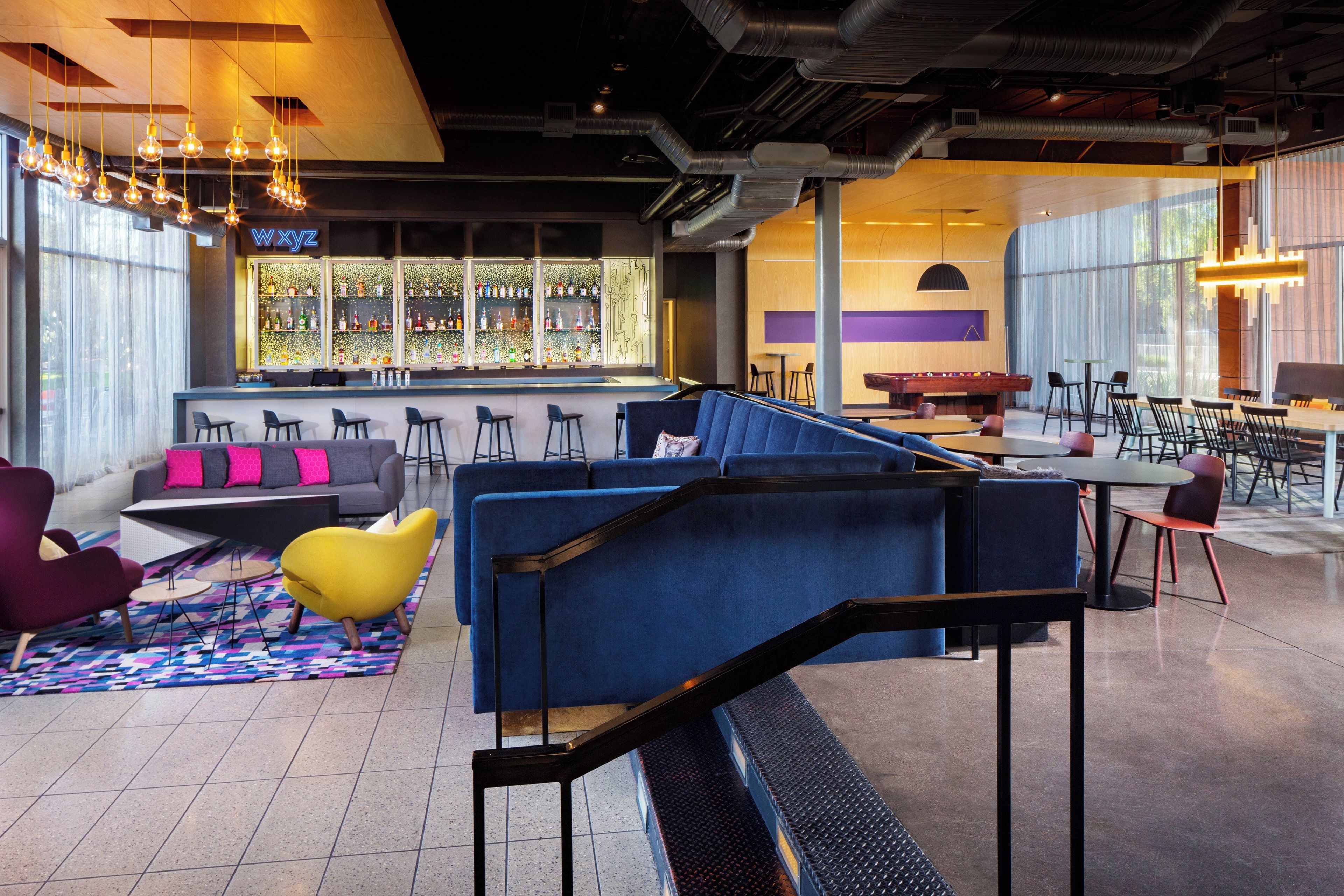 A modern bar area with seating, a pool table, and a bar stocked with various bottles.