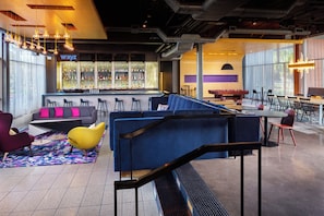 A modern bar area with seating, a pool table, and a bar stocked with various bottles. - Aloft by Marriott Tempe (Tempe)