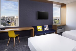 A hotel room with a bed, a desk with a chair, a TV, and a window with a city view. - Aloft by Marriott Tempe (Tempe)
