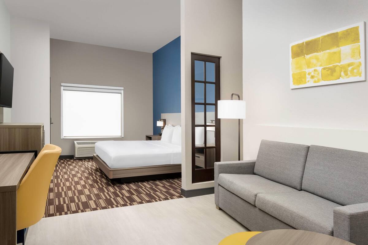 A hotel room with a bed, a sofa, a desk, and a TV.