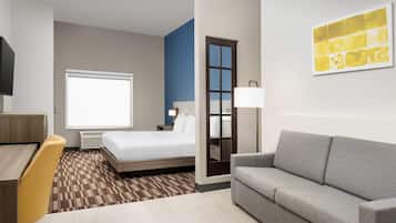 A hotel room with a bed, a sofa, a desk, and a TV.