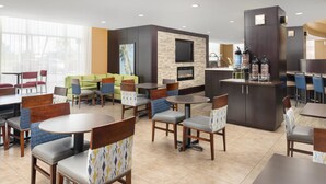 A modern hotel lobby with a fireplace, seating areas, and a bar.