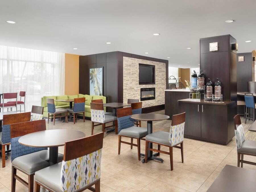 A modern hotel lobby with a fireplace, seating areas, and a bar.