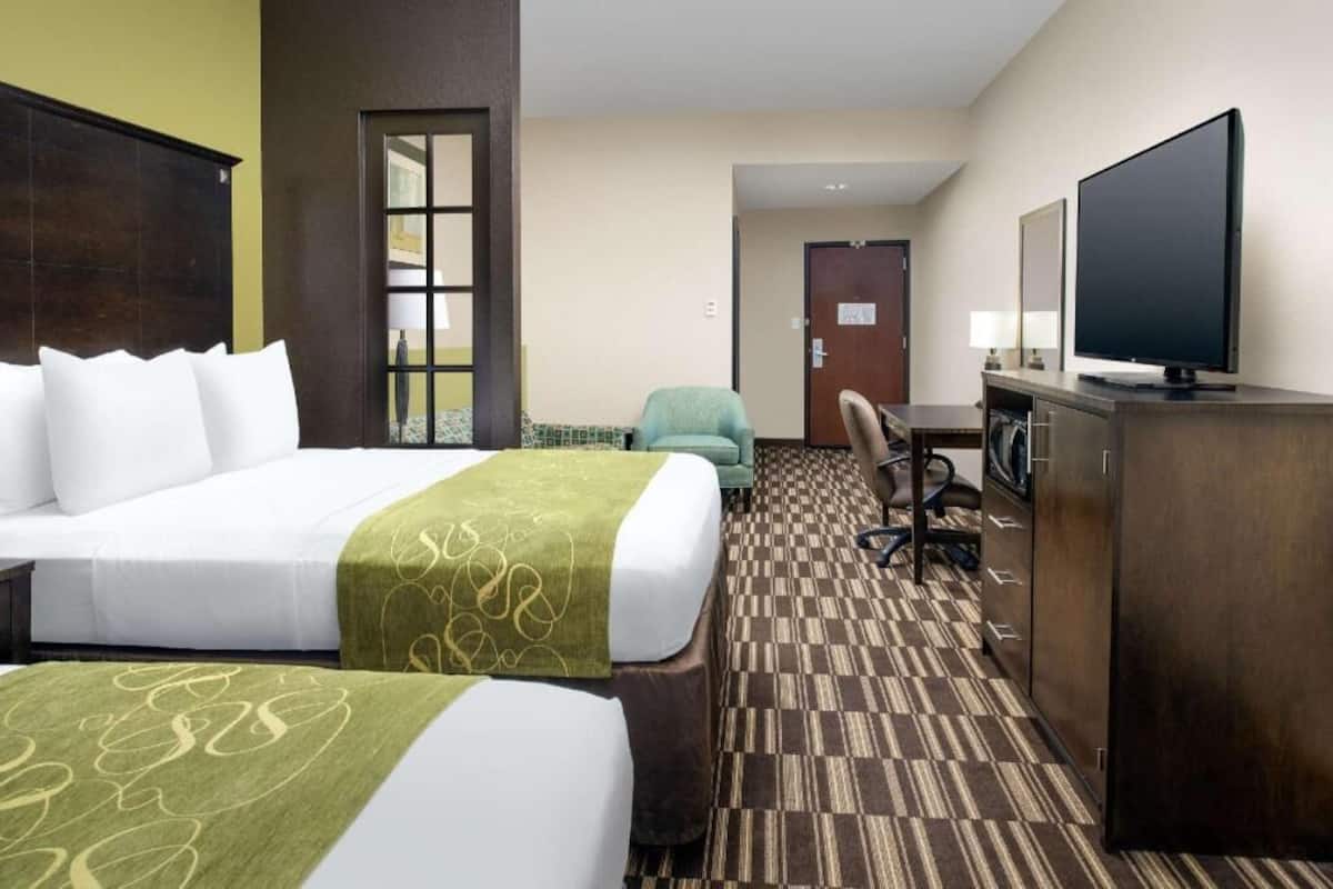 A hotel room with a bed, a desk, a television, and a chair.