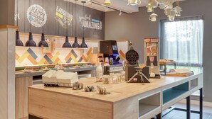A modern kitchen area with a long counter, hanging pendant lights, and motivational wall quotes. - Hampton by Hilton Corby/Kettering (Corby)