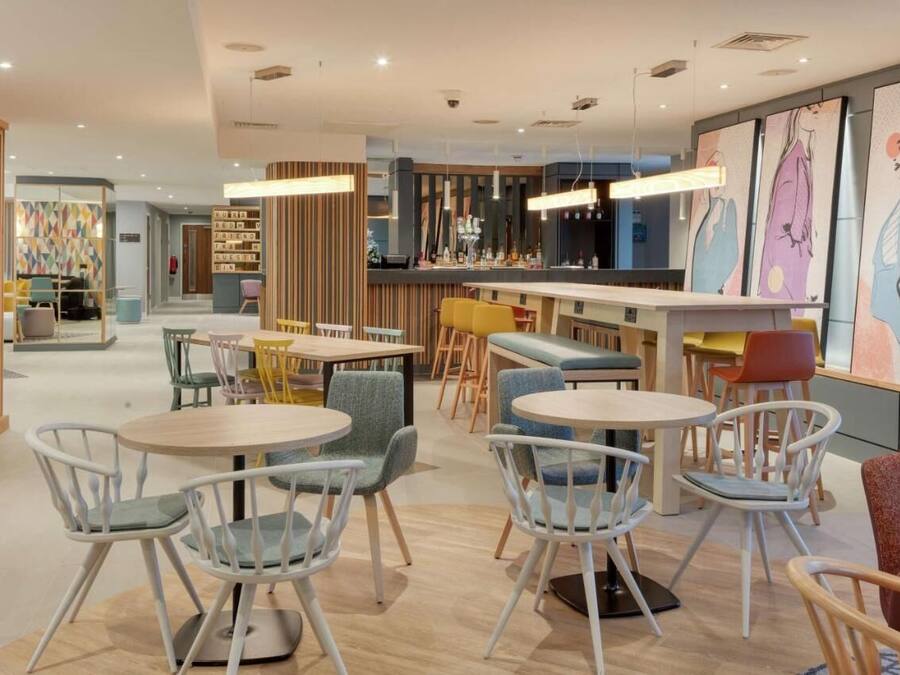 A modern interior with round tables and chairs, a bar area, and artwork on the walls.