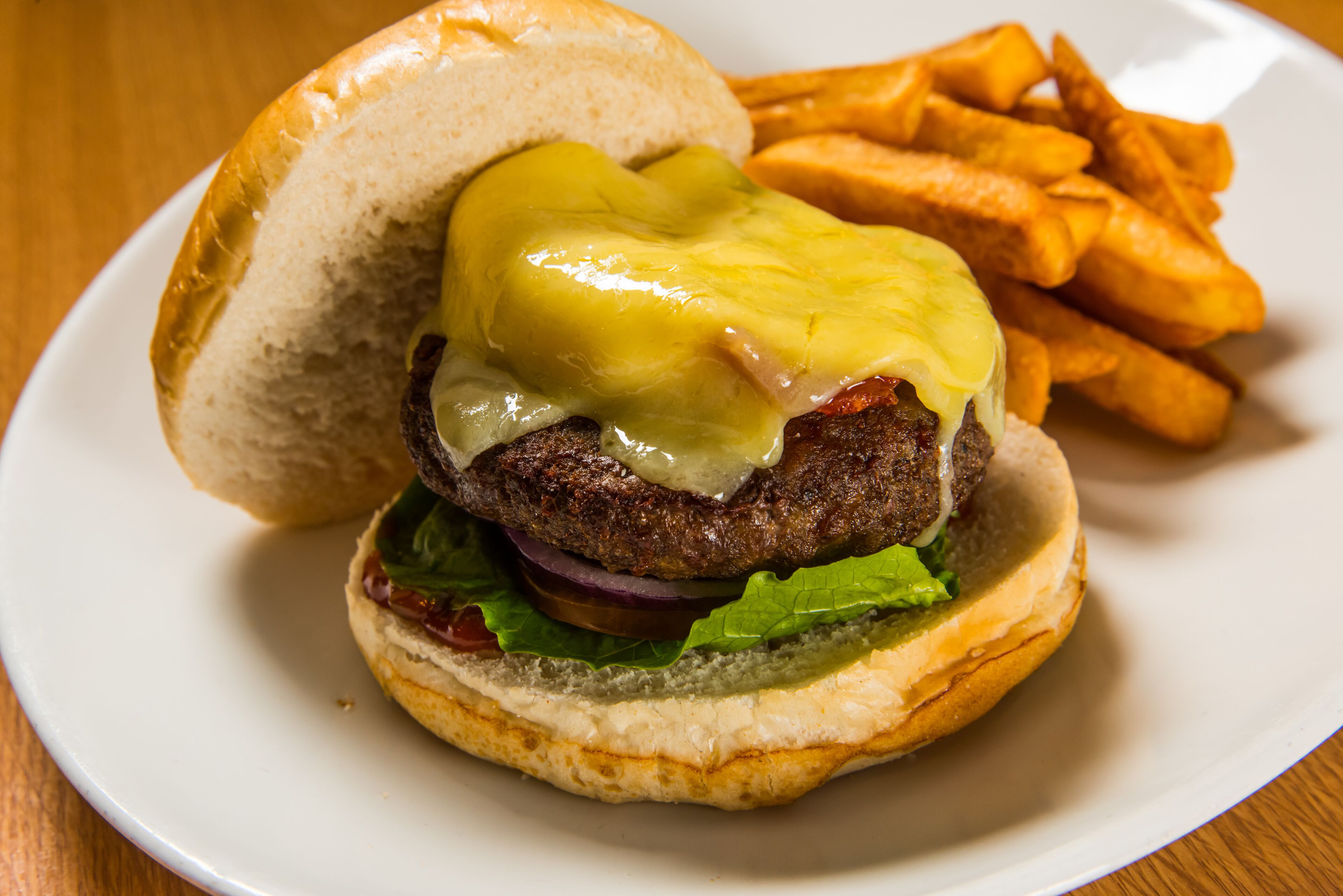 Un hamburger au fromage et à la moutarde, accompagné d’une portion de frites.