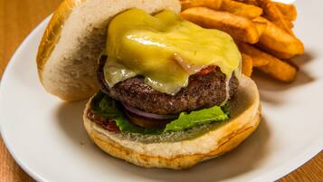 Hamburguesa con queso y mostaza, acompañada de papas fritas.