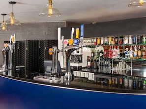 A bar area with a counter, taps, and a variety of bottles.