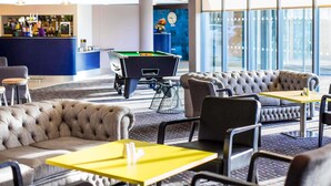 Een moderne lounge met een pooltafel, zithoek en bar.