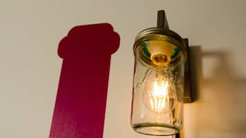 Una lámpara de pared con estructura de vidrio y bombilla de filamento visible.