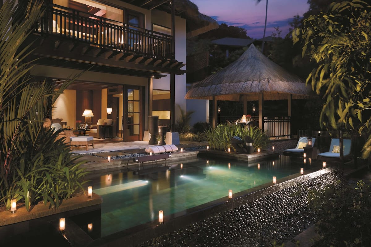 Ein modernes Resort mit Schwimmbad, Lounge-Bereich und einem Gazebo mit Reetdach.