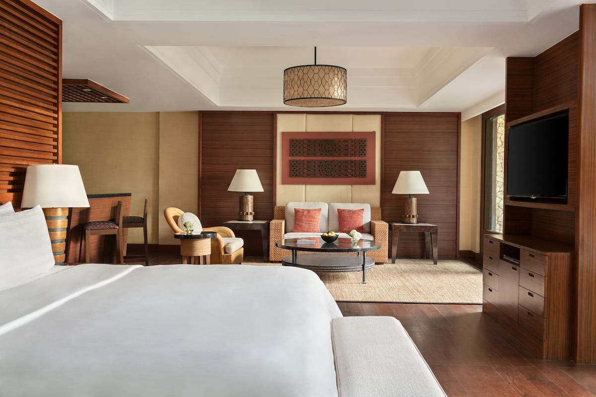 Ein Hotelzimmer mit einem großen Bett, zwei Sesseln, einer Couch, einem Couchtisch, einem Fernseher und einem Kamin.
