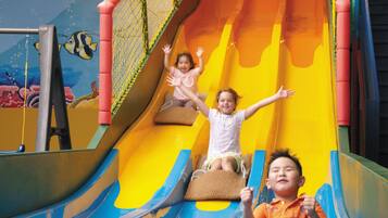 Un toboggan d’intérieur pour enfants, doté de plusieurs pistes, de parois en filet et d’un design coloré.