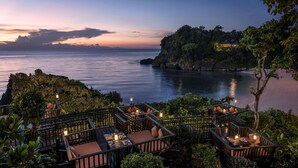 A seaside resort with outdoor seating areas overlooking the ocean.