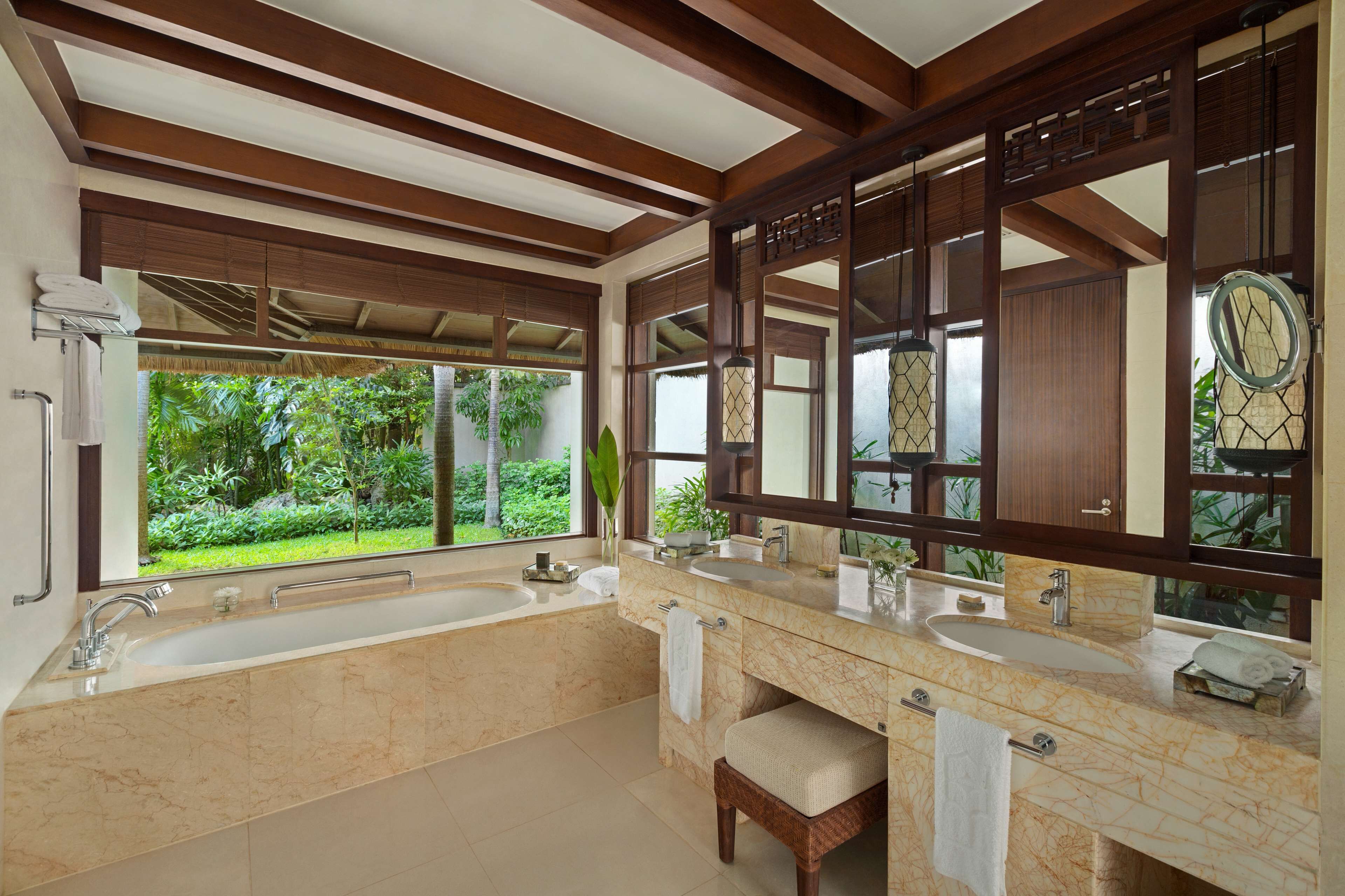 A spacious bathroom with two sinks, a large bathtub, and a wooden ceiling.