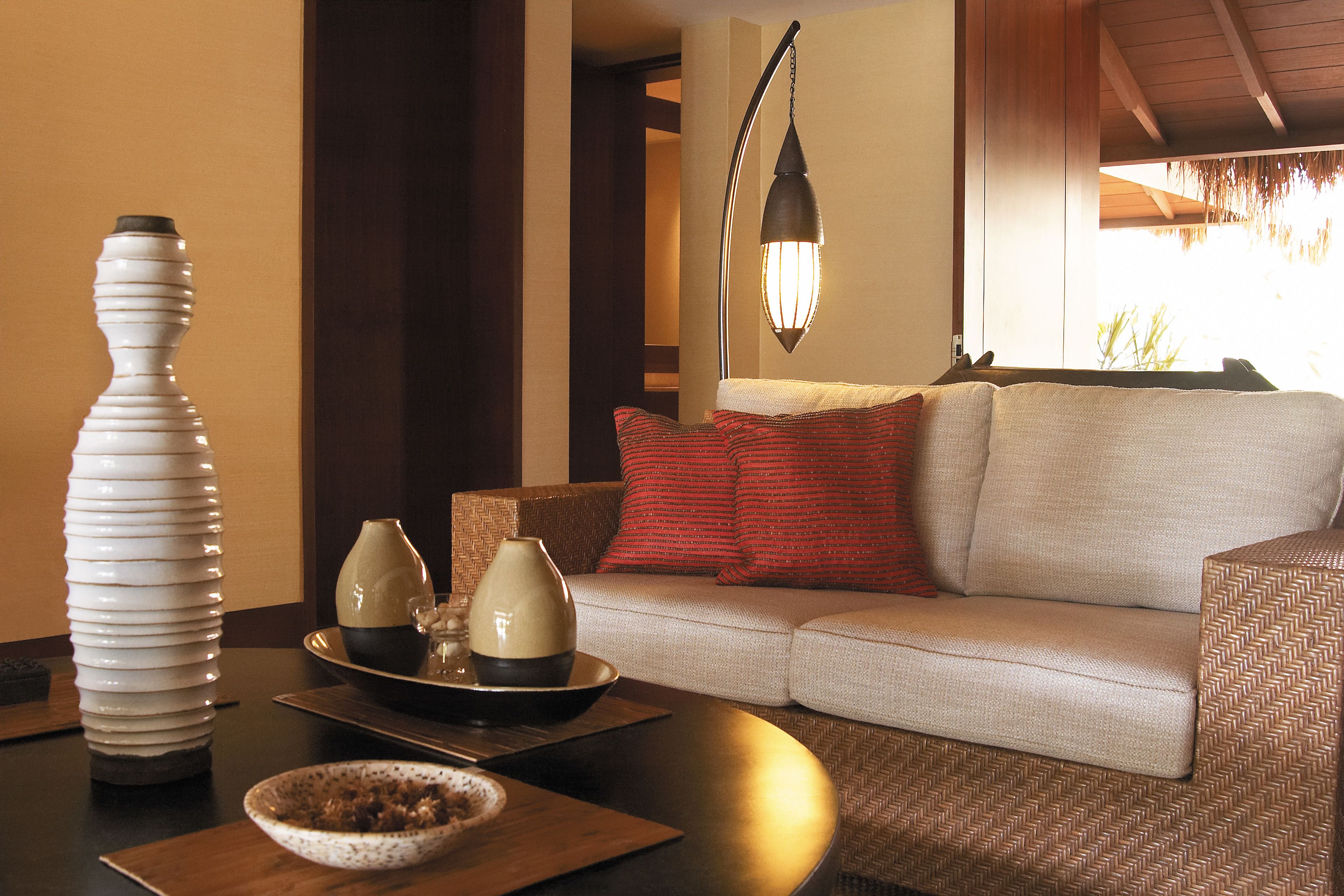A modern living room with a sofa, decorative vases, and a table with a bowl.