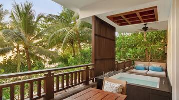 A balcony with a wooden table and chairs, a small pool, and a sofa with cushions.