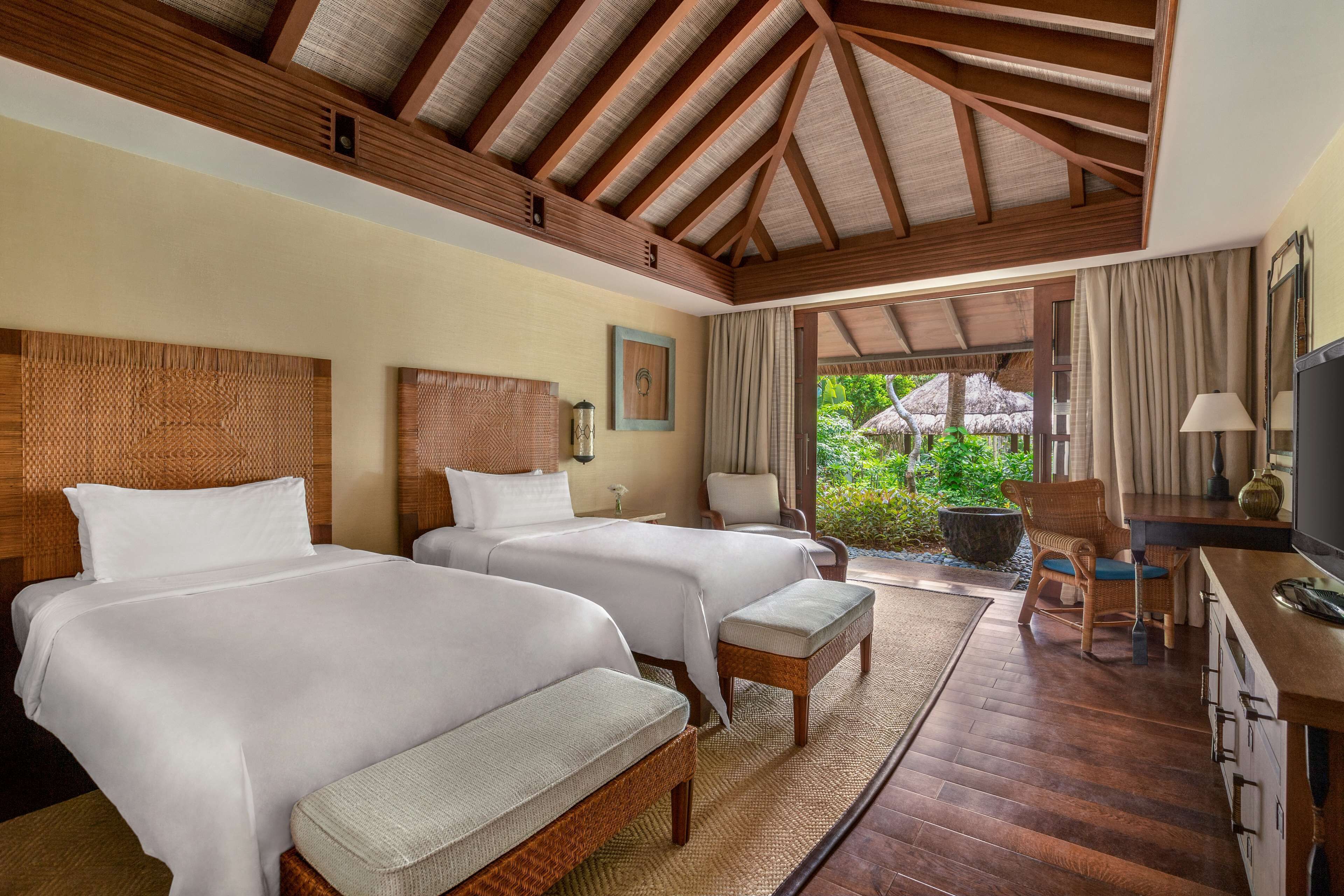A hotel room with two beds, a desk, and a chair.