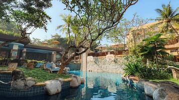 A pool area with clear water, surrounded by rocks and greenery, and a building with a sign that reads "Paradiso".