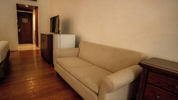 A room with a beige sofa, a wooden dresser, and a small white cabinet.