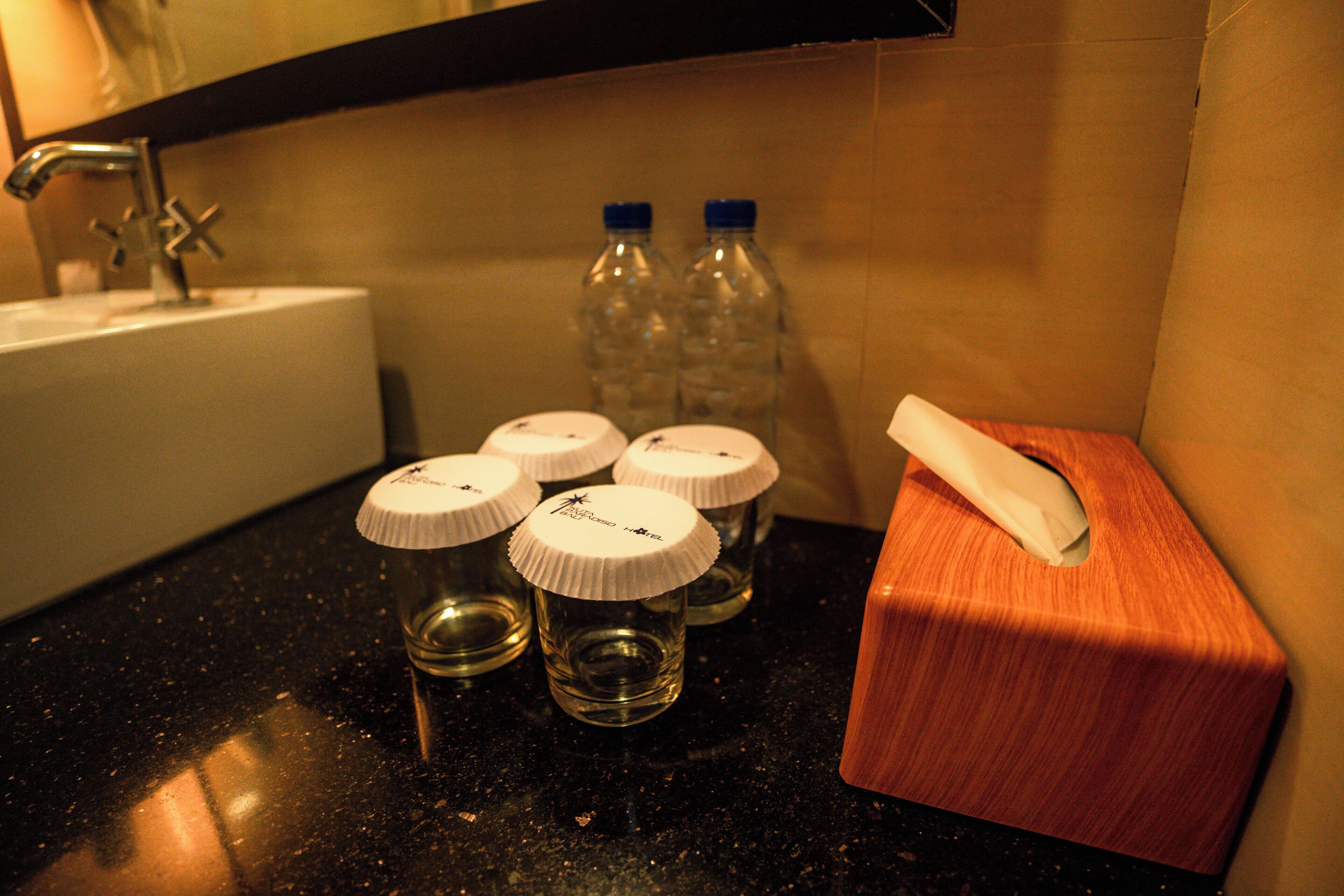 A bathroom sink with four bottles of water and a tissue box on a countertop.