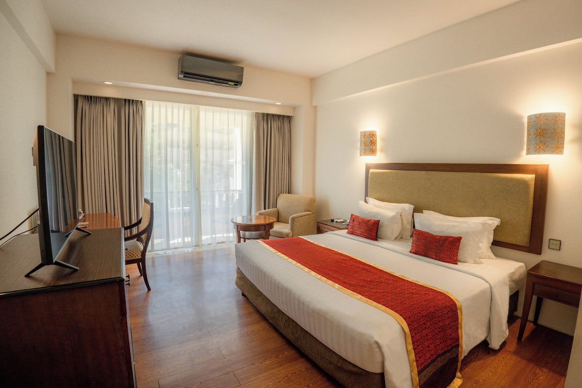 Habitación de hotel con una cama grande, un escritorio, una silla y un televisor.