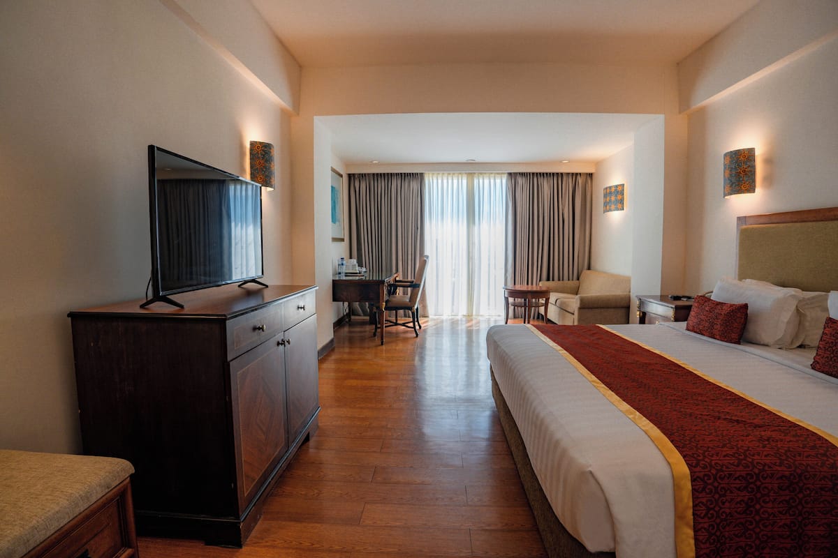 Una habitación de hotel con cama, escritorio, silla, televisor y armario.
