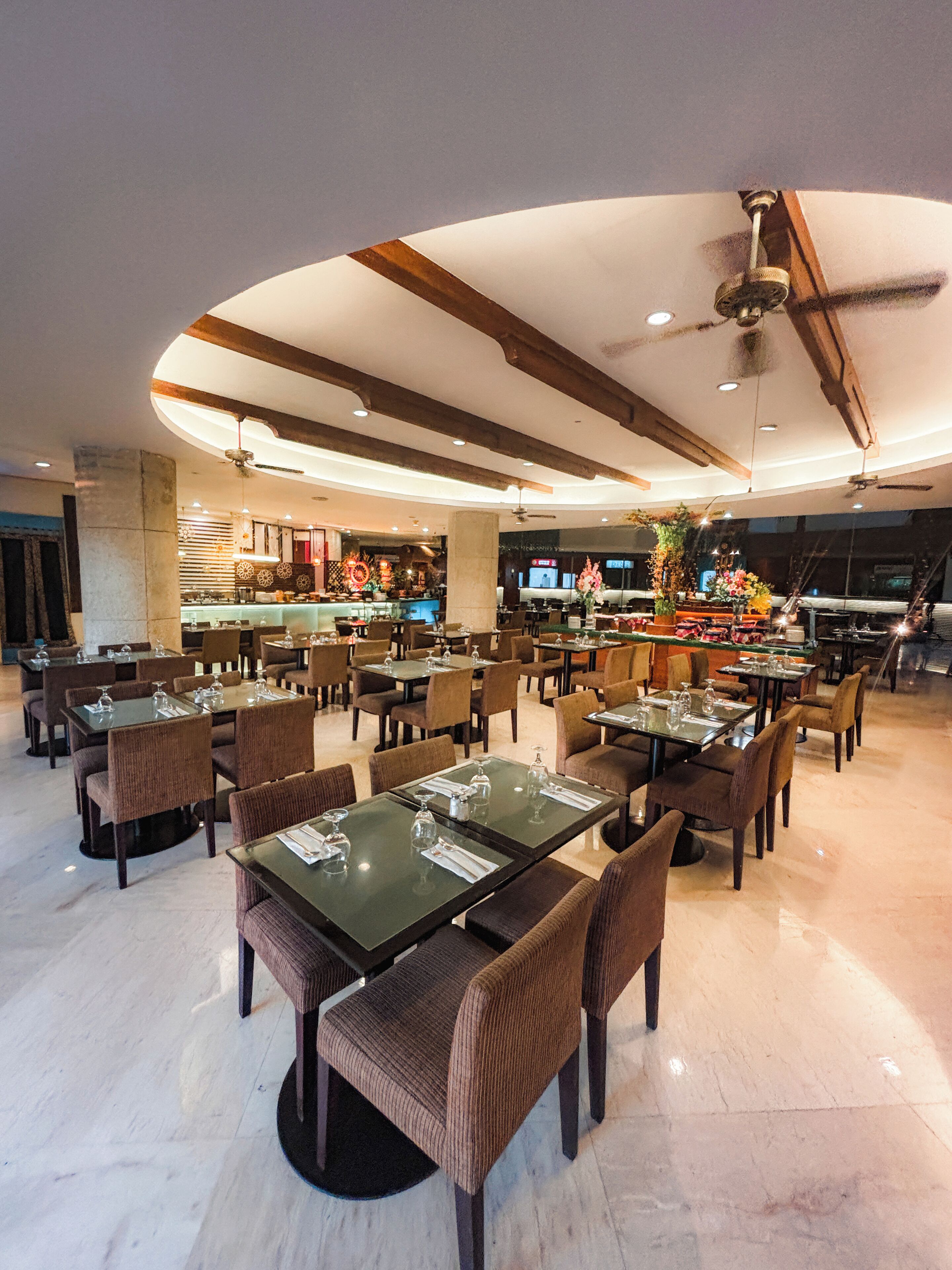 Un restaurant spacieux, doté de nombreuses tables et chaises, d’un bar et d’un ventilateur de plafond.