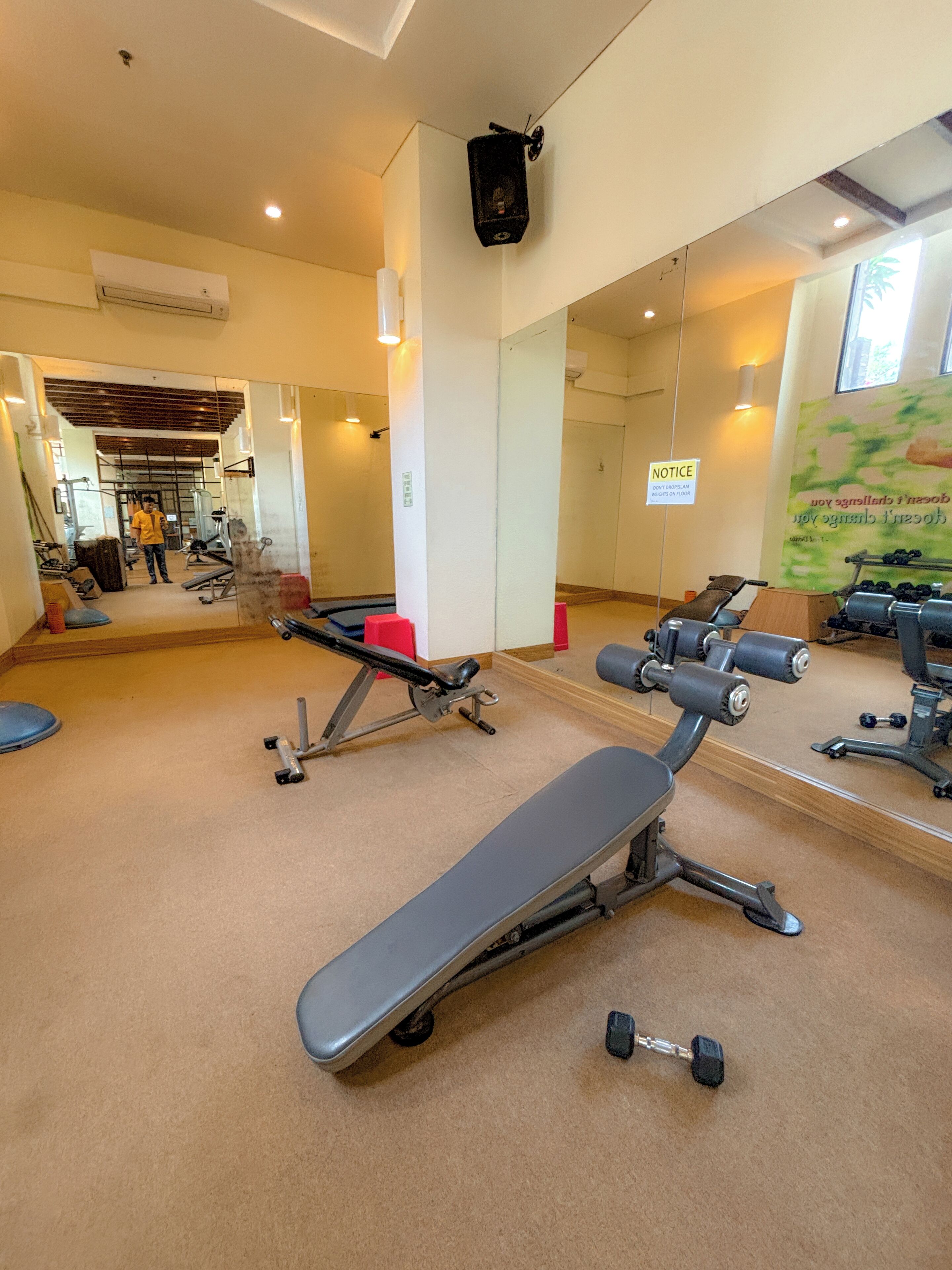 Een sportschool met fitnessapparatuur, een bank en een spiegel.