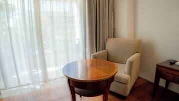 A room with a round wooden table, a beige armchair, and a small wooden side table.